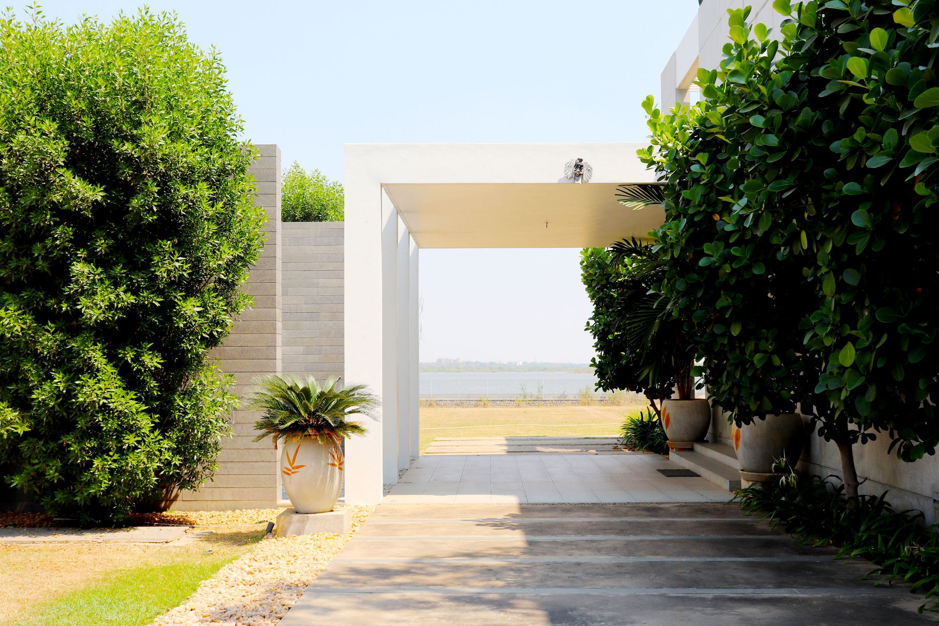 A contemporary driveway with lush greenery leading to a modern home entrance.